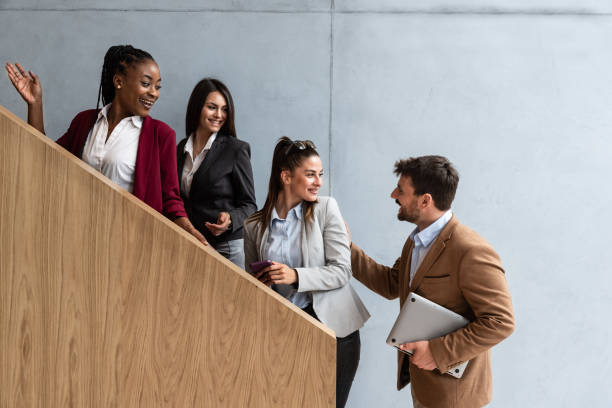 A small, diverse team of professionals engages in a positive conversation while ascending a staircase.